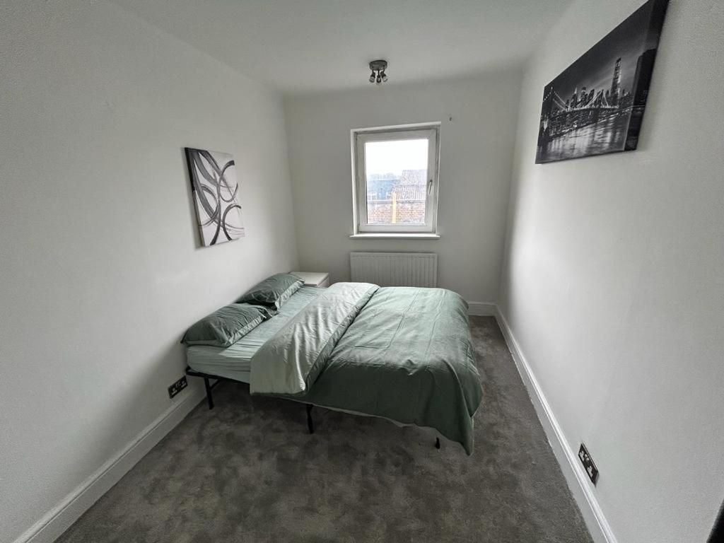 1 dormitorio con cama y ventana en 4 Bedroom Flat In Watford en Leavesden Green