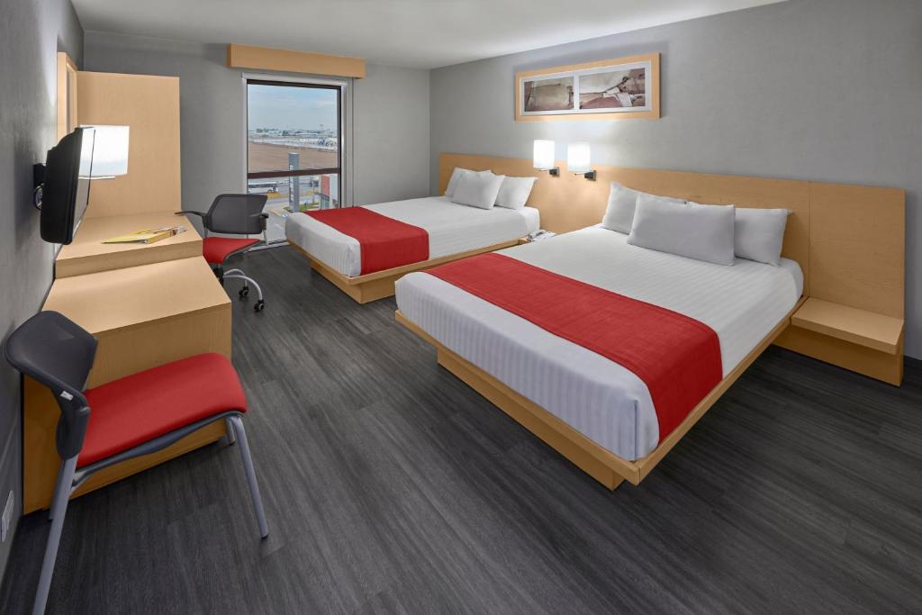 a hotel room with two beds and a desk at City Express by Marriott Torreon in Torreón