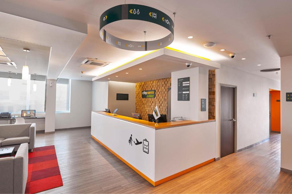 an office lobby with a reception counter and chairs at City Express Junior by Marriott San Luis Potosi Carranza in San Luis Potosí