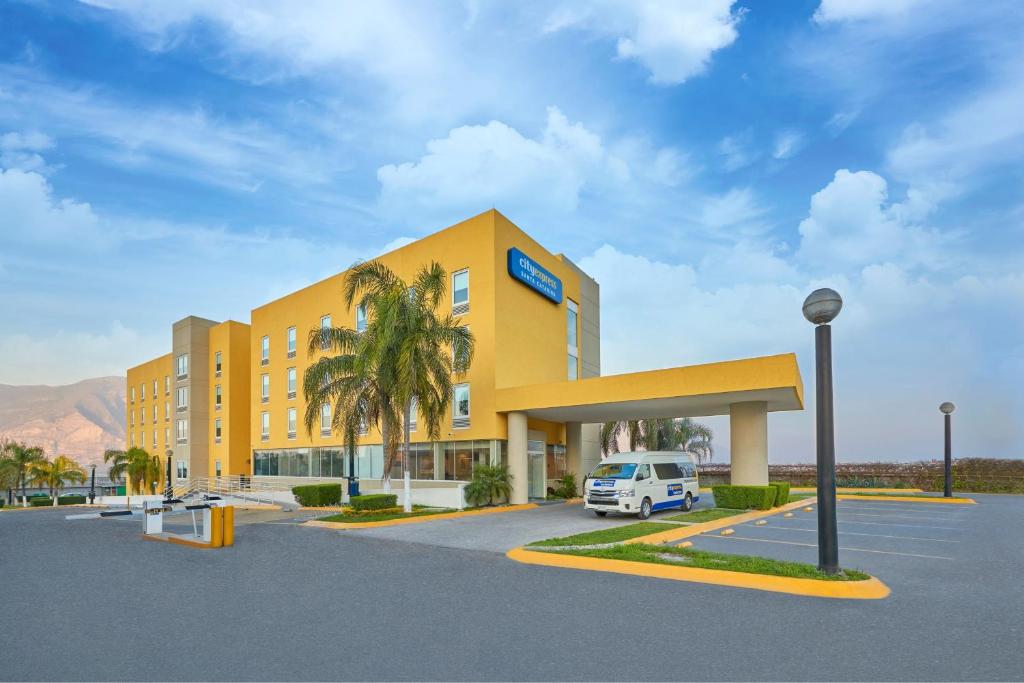 un hotel amarillo con una furgoneta blanca estacionada en un estacionamiento en City Express by Marriott Monterrey Santa Catarina en Monterrey