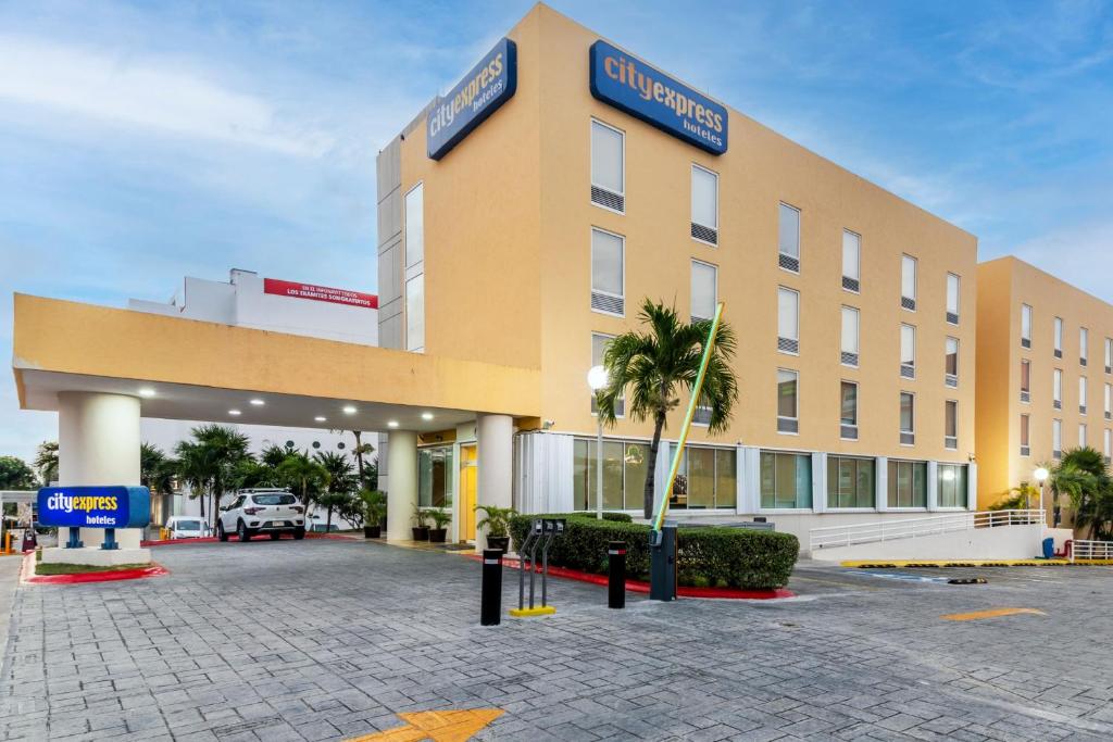 un grand bâtiment avec un parking en face de celui-ci dans l'établissement City Express by Marriott Cancun, à Cancún