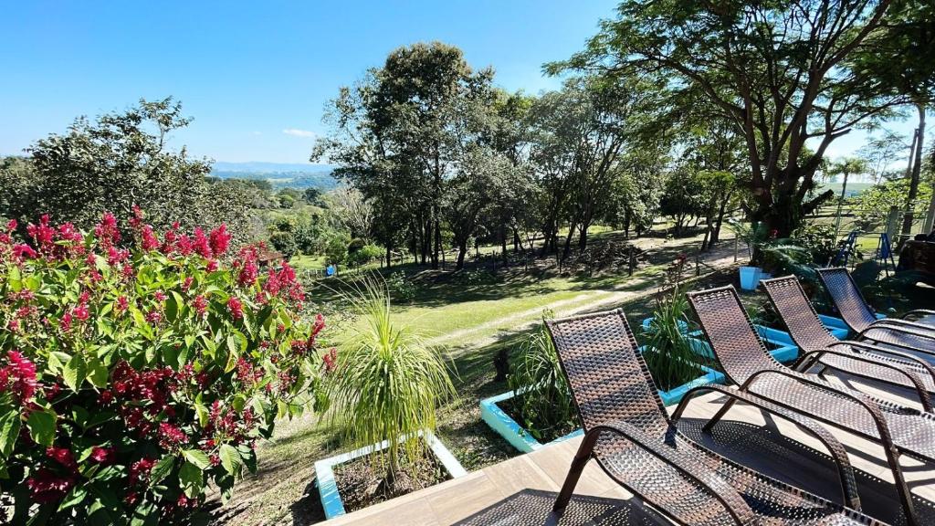 a group of chairs sitting on a patio with flowers at Chácara Sonho Realizado in São Pedro