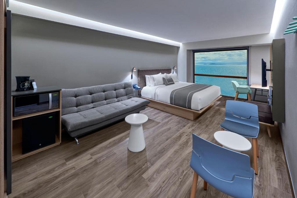 Habitación de hotel con cama y sofá en City Express Plus by Marriott Ensenada en Ensenada