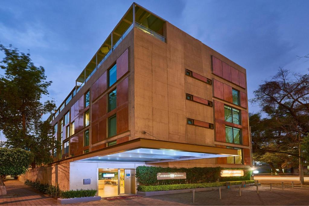 un edificio alto con una fachada iluminada en City Express Suites by Marriott Anzures en Ciudad de México