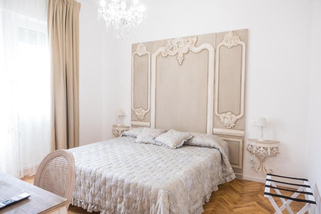 a white bedroom with a bed and a chandelier at Althea in Viareggio