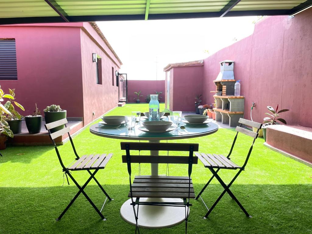 a patio with a table and chairs on the grass at Casa Rural La CaTaTa in Las Lagunas
