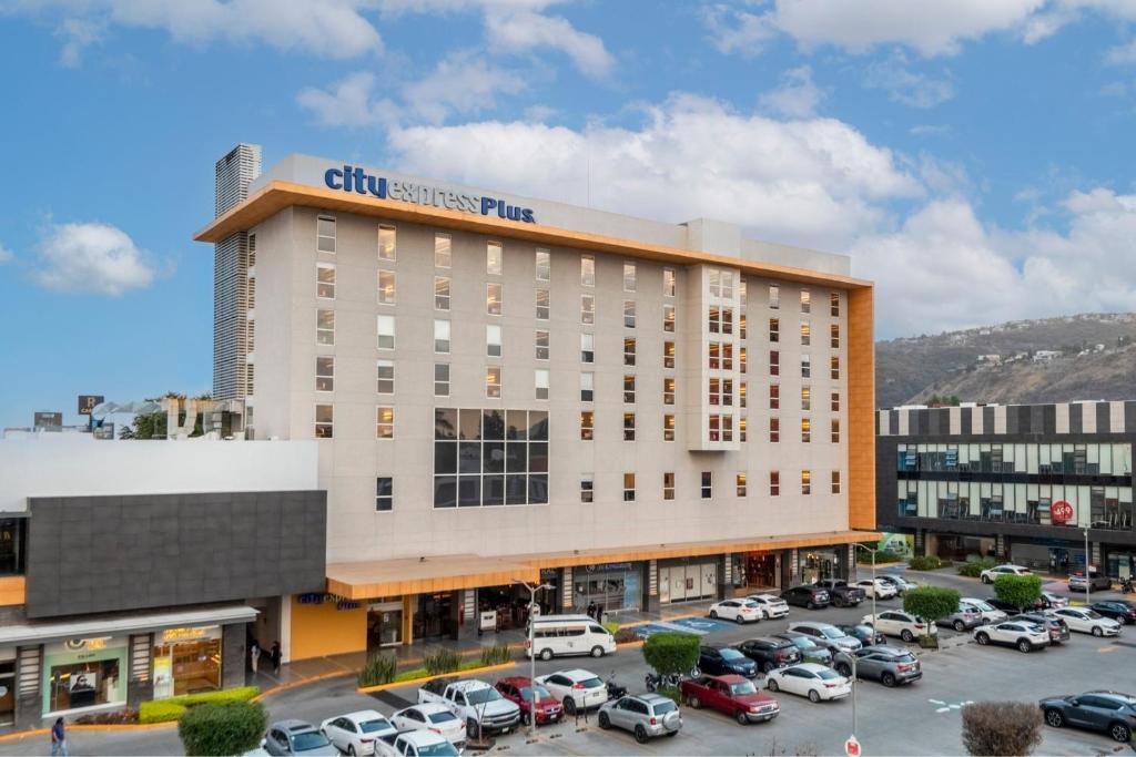 a large building with cars parked in a parking lot at City Express Plus by Marriott Guadalajara Palomar in Guadalajara