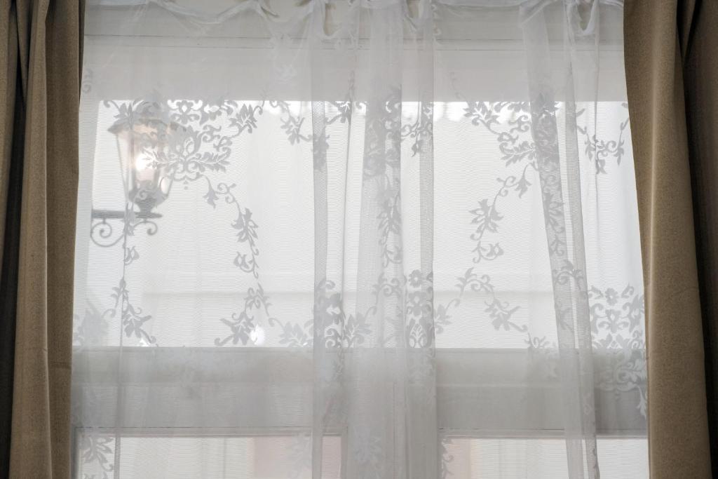 a window with a white curtain and a lamp at Althea in Viareggio