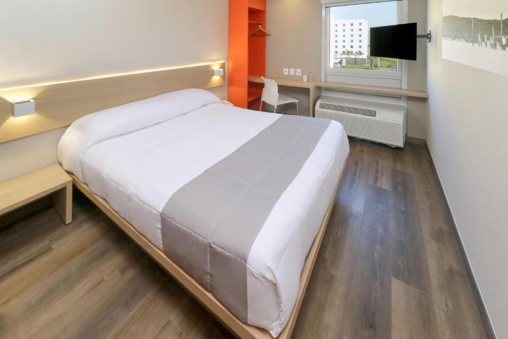 um quarto com uma grande cama branca num quarto em City Express Junior by Marriott Tijuana Otay em Tijuana