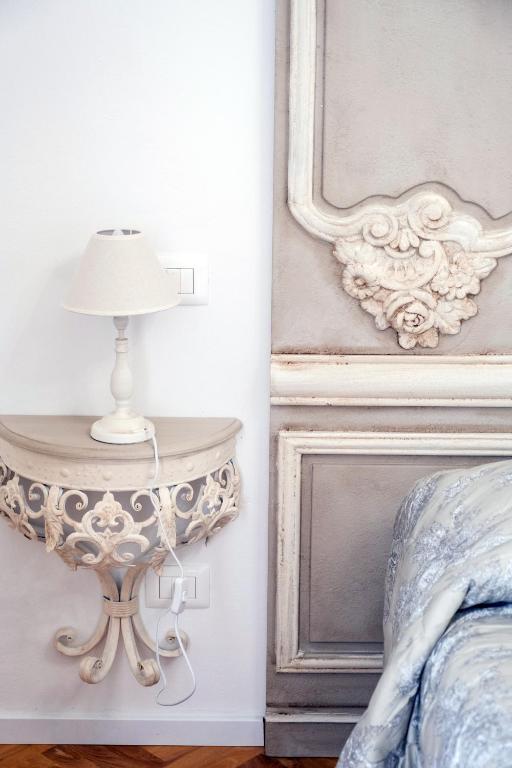 a table with a lamp on it next to a bed at Althea in Viareggio
