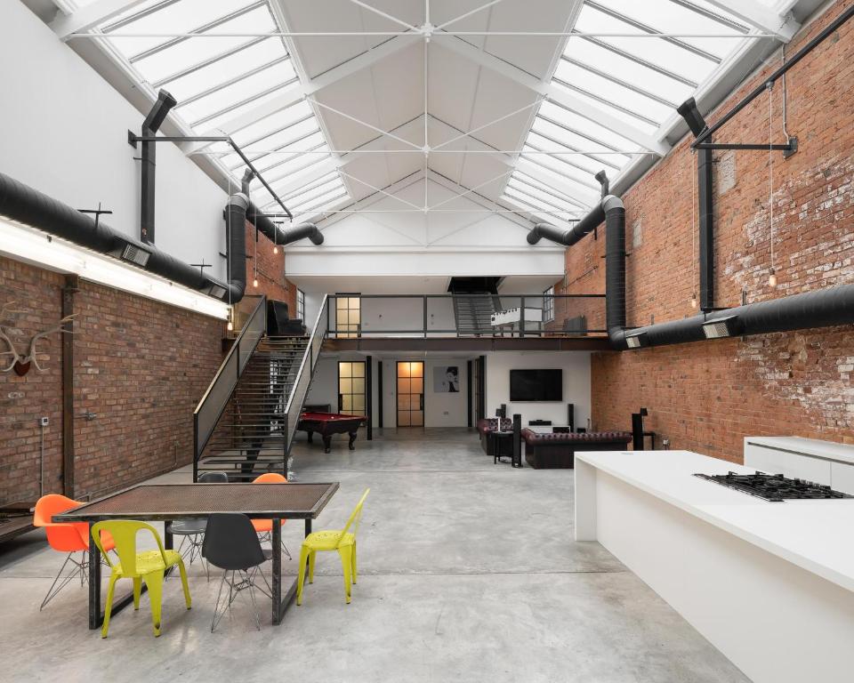 an industrial loft with a staircase and tables and chairs at Bedford Street Lofts in Leamington Spa