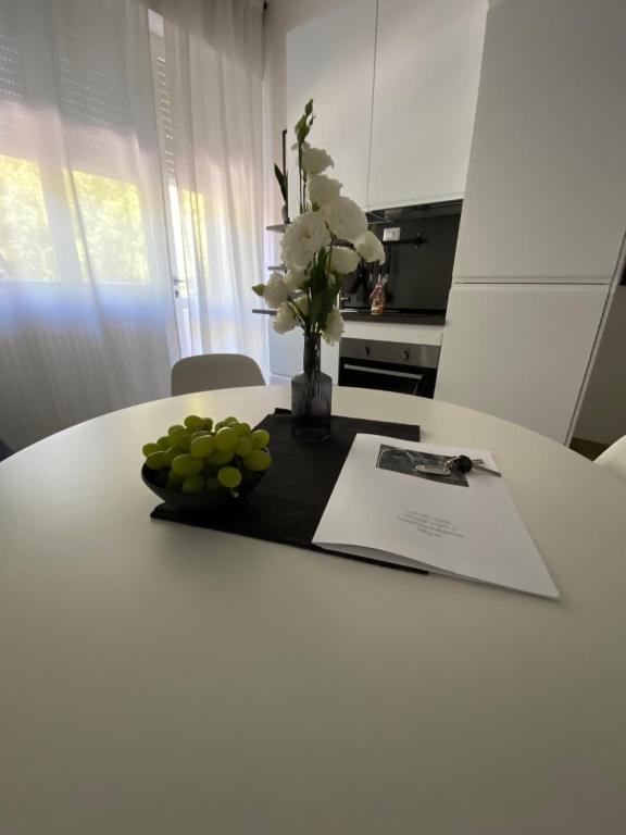 a table with a vase of flowers and a plate of grapes at Casettadellafotografia in Senigallia