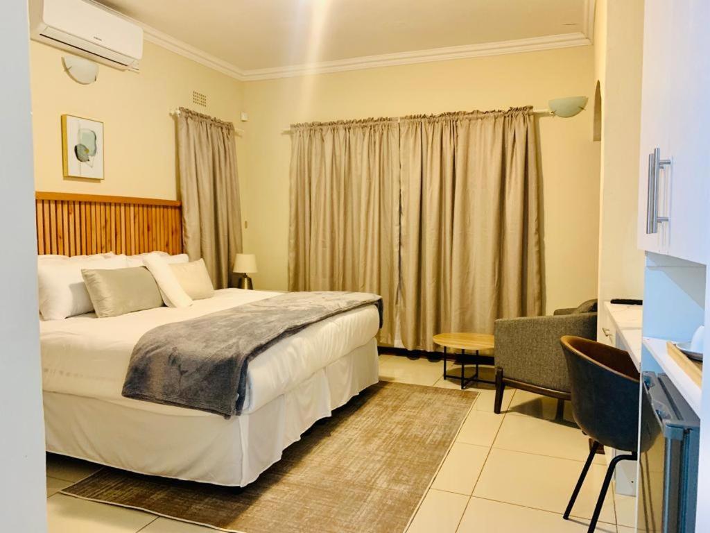 ein Hotelzimmer mit einem großen Bett und einem Schreibtisch in der Unterkunft Mmaset Houses bed and breakfast in Gaborone