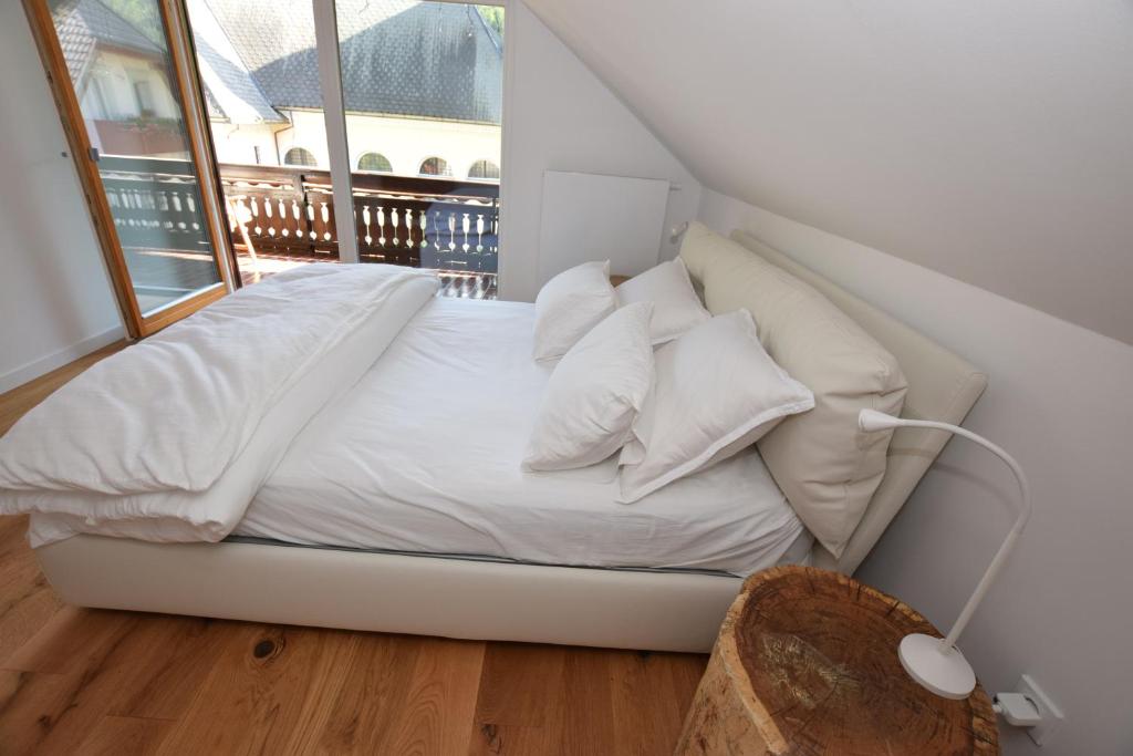 a bed with white sheets and pillows in a room with a window at EROS APARTMENT Kranjska Gora in Kranjska Gora