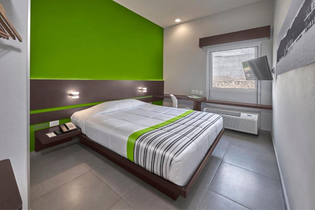 une chambre avec un grand lit avec un mur végétal dans l'établissement City Express Junior by Marriott Cancun, à Cancún