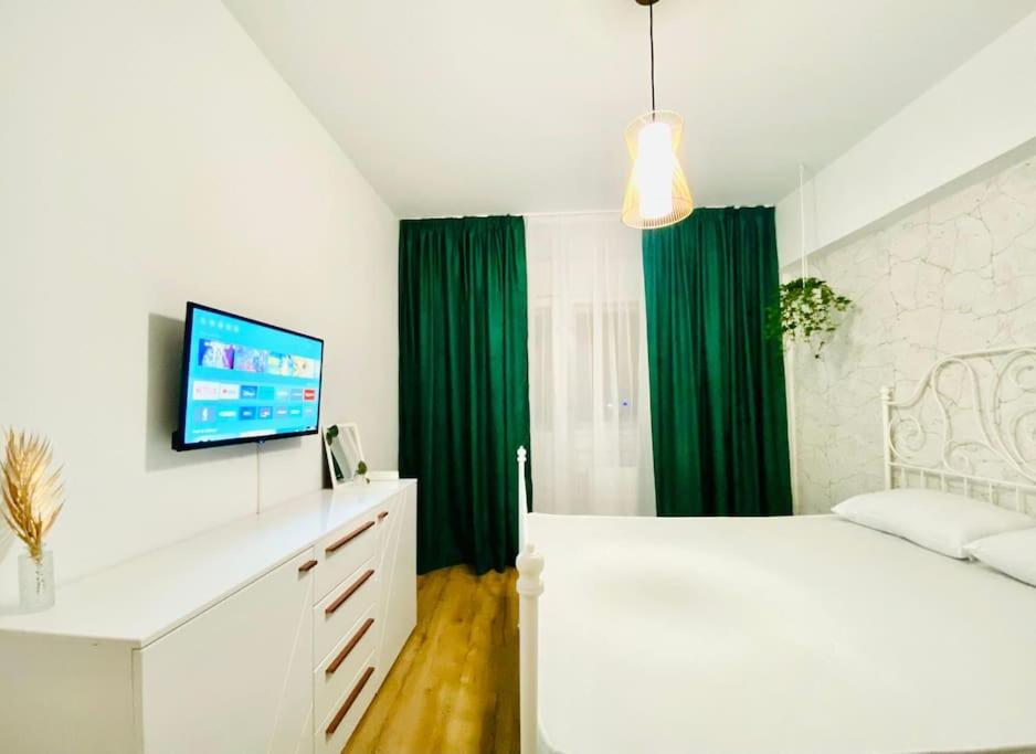 Schlafzimmer mit einem weißen Bett und grünen Vorhängen in der Unterkunft Union Experience - City Center in Timişoara