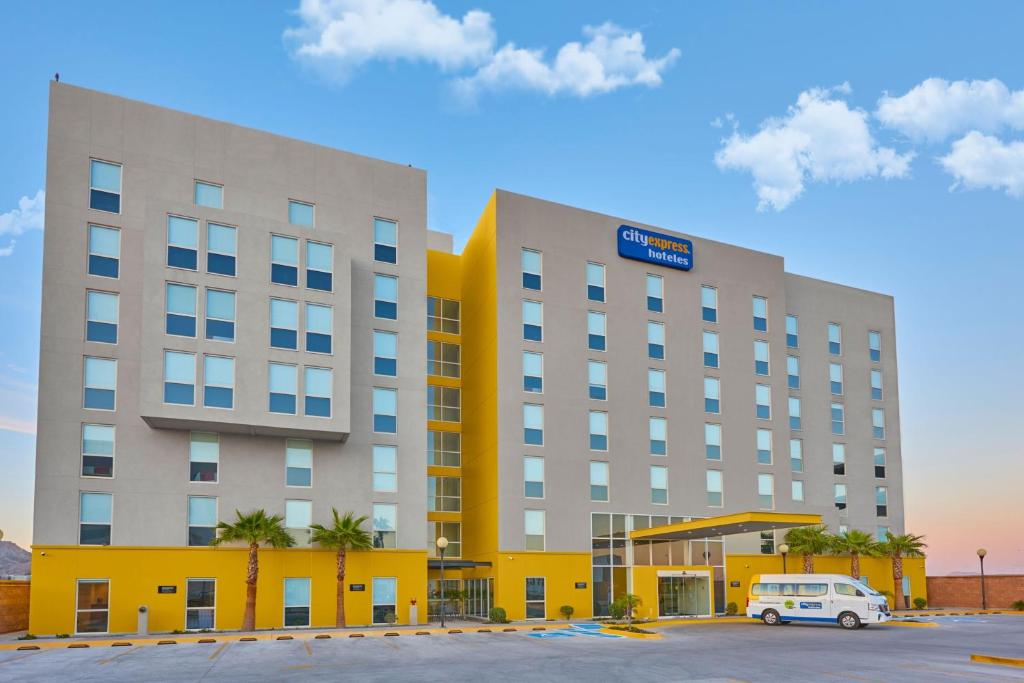 a hotel with a van parked in a parking lot at City Express by Marriott Hermosillo Expo in Hermosillo