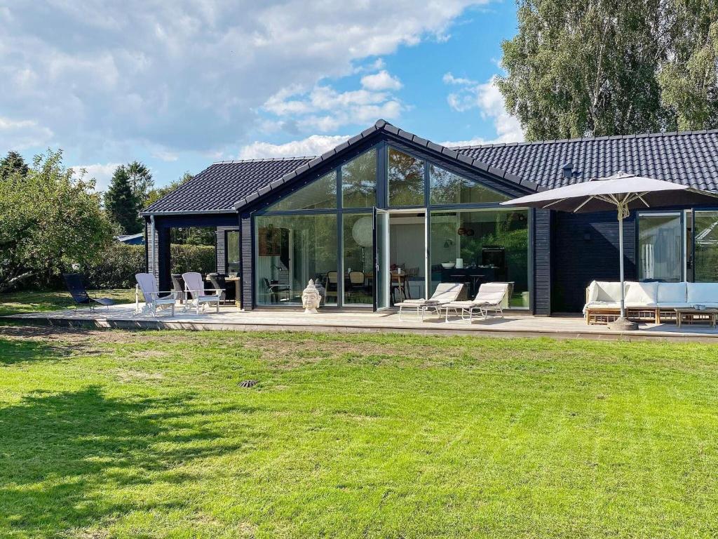 a house with a conservatory with chairs and an umbrella at Family Holiday Home in Juelsminde in Juelsminde