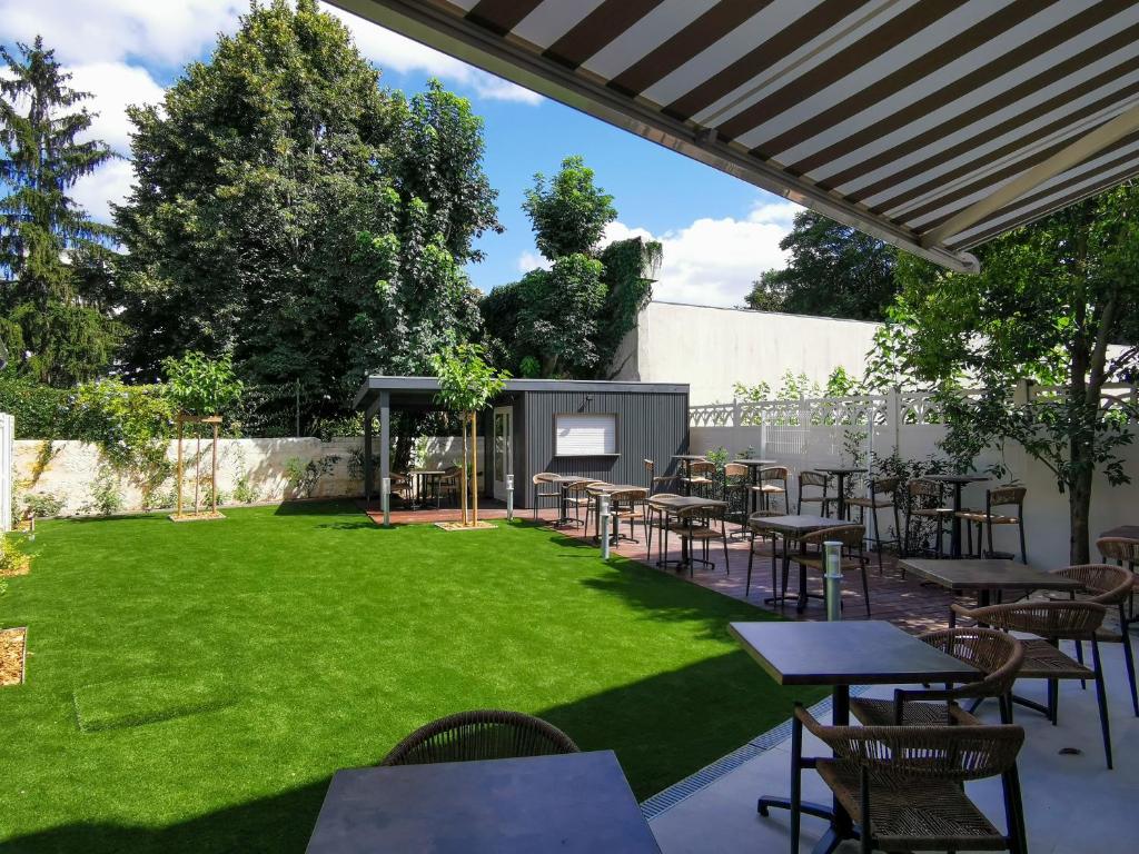 een gazon met tafels en stoelen en een scherm bij Bloom Hostel Bar & Garden in Bordeaux