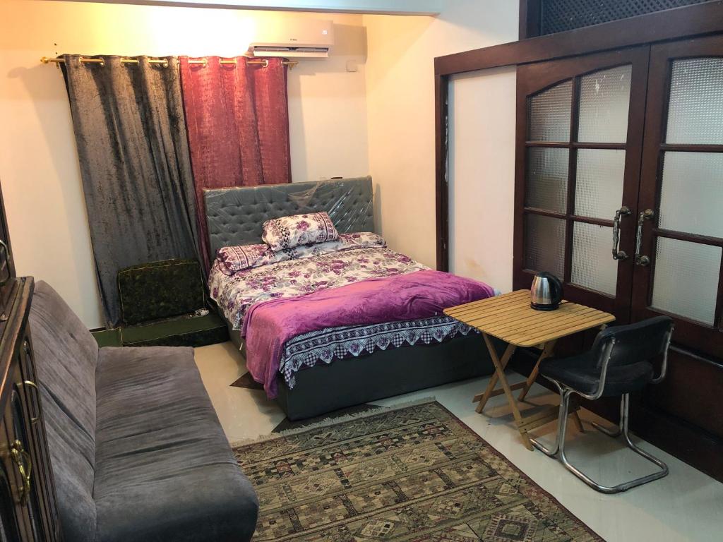 a bedroom with a bed and a table and chair at Zagazig in Manshīyat as Sādāt