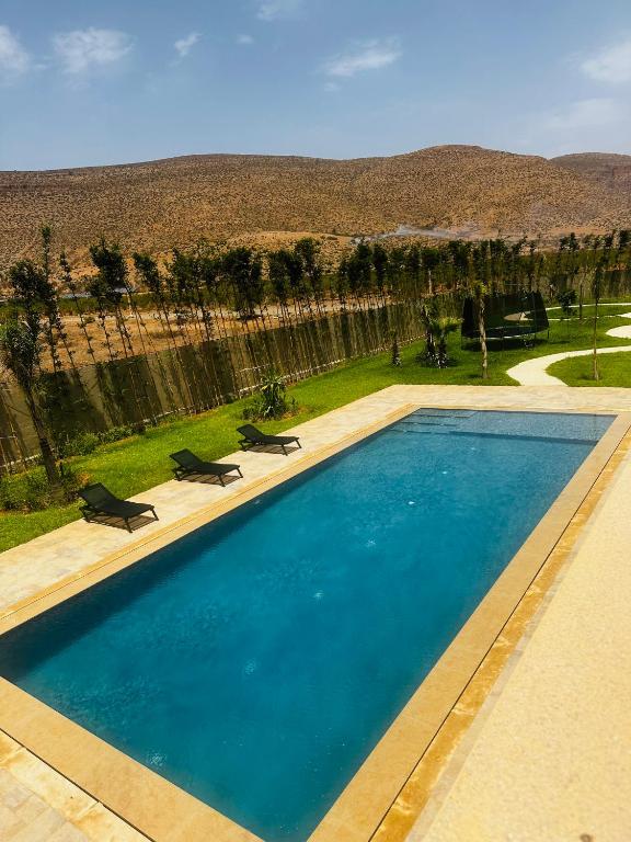 a large blue swimming pool with two chairs in a yard at Villa Dream Oujda Piscine Chauffée sans vis à vis in Oujda