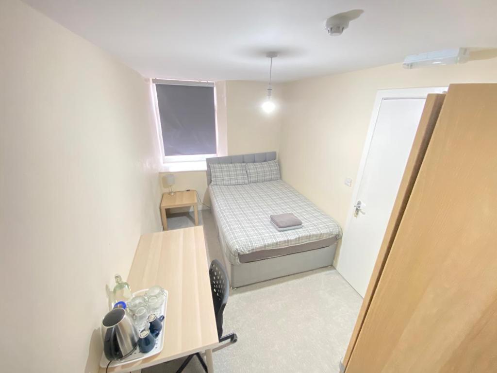 a small room with a small bed and a table at Rangers GuestHouse in Glasgow