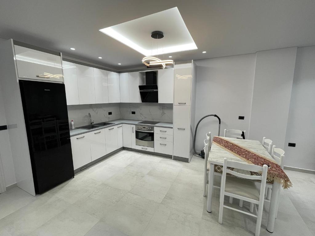 a kitchen with white cabinets and a table with chairs at Alpha Lux Apartment in Sarandë