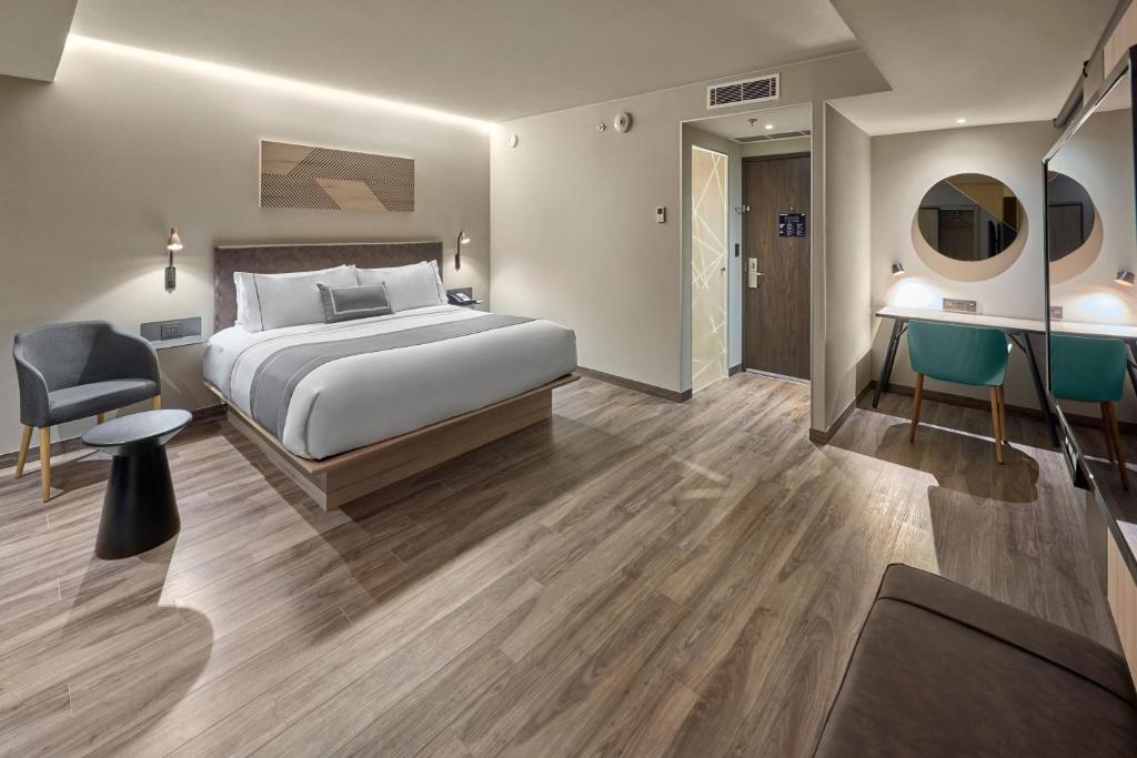 a hotel room with a bed and a desk at City Express Plus by Marriott Merida in Mérida