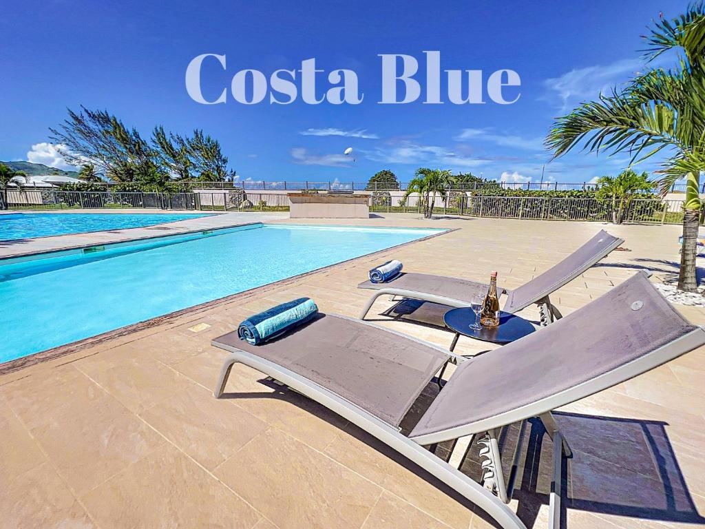a swimming pool with two lounge chairs next to a pool at Costa Blue, Orient Bay beach front, XXL pools in Orient Bay