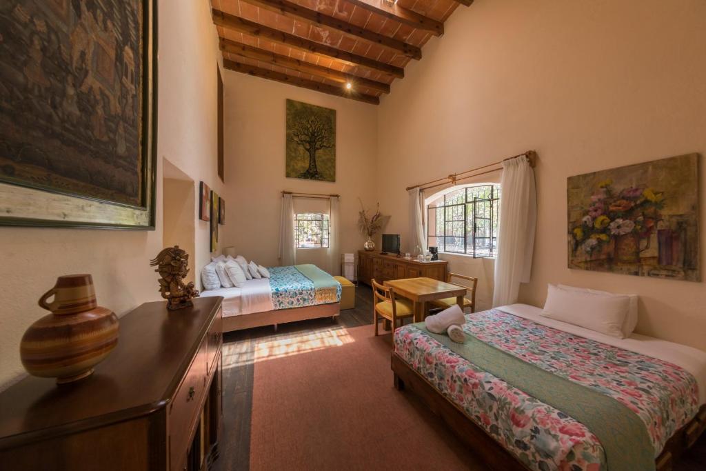 Un dormitorio con dos camas y un escritorio y una mesa. en Meztli: Casa Boutique & Spa, en Ciudad de México