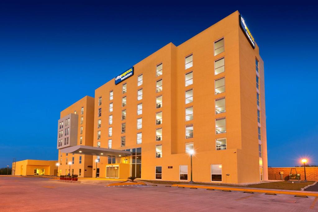 um grande edifício de hotel laranja à noite em City Express by Marriott Reynosa Aeropuerto em Reynosa