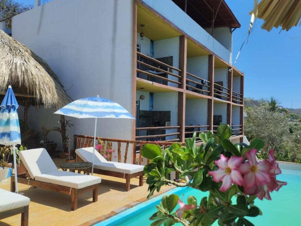 a resort with a pool and chairs and a building at Namasté Zipolite Suites in Zipolite