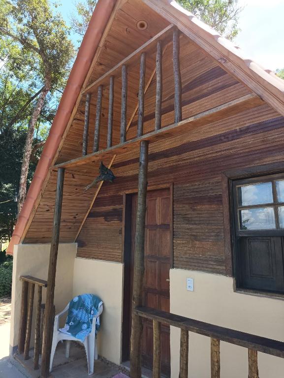 a wooden cabin with a blue chair in front of it at Chalé do Mirante do Itacolomi in Ouro Preto