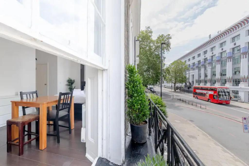 a balcony with a wooden table and a red bus at Incredibly Located Studio Flat - Camden Town in London