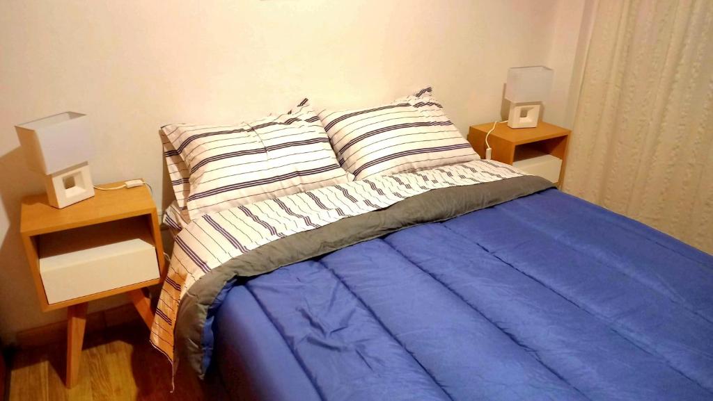 ein Schlafzimmer mit einem blauen Bett und zwei Nachttischen in der Unterkunft BeelApt - Departamento elegante y seguro, con Cochera Exclusiva in La Plata