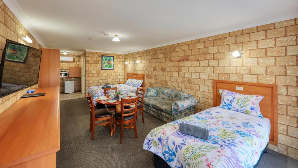 a bedroom with a bed and a table and a kitchen at Darling River Motel in Bourke