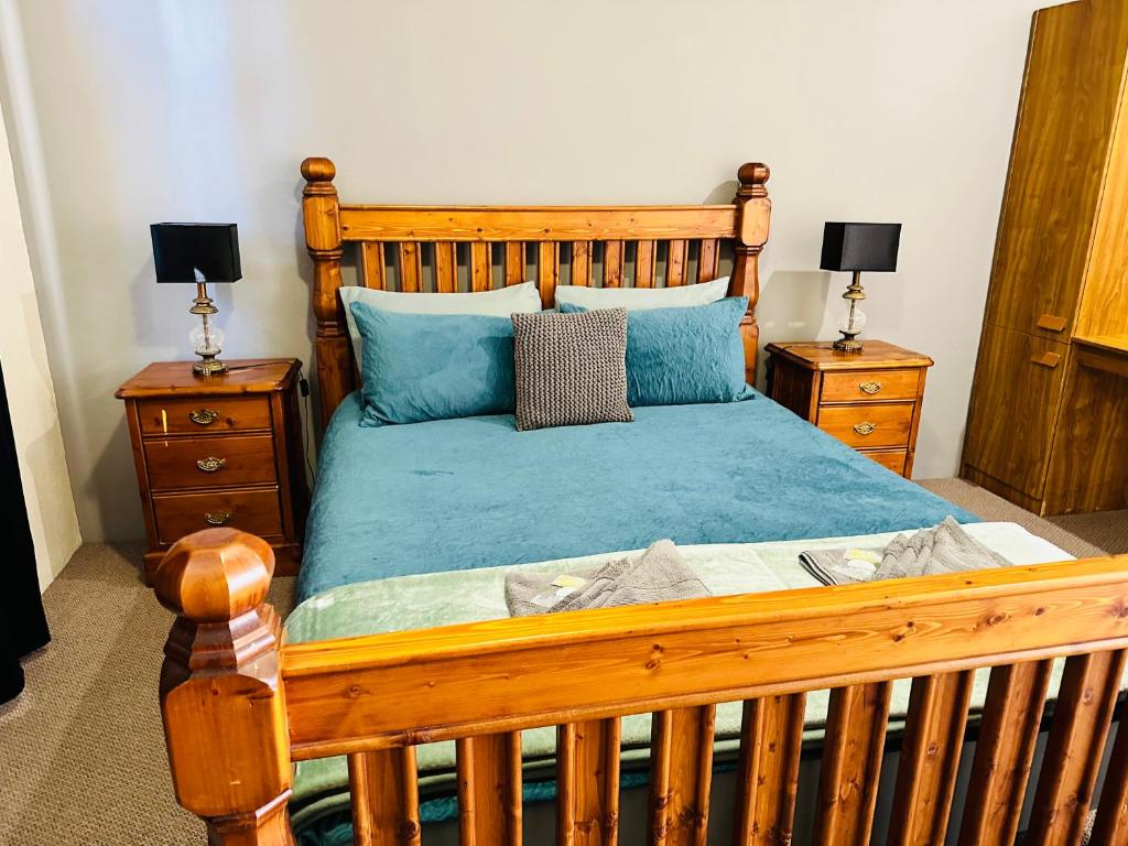 - une chambre avec un lit en bois et 2 tables de chevet dans l'établissement Flinders Ranges Motel - The Mill, à Quorn