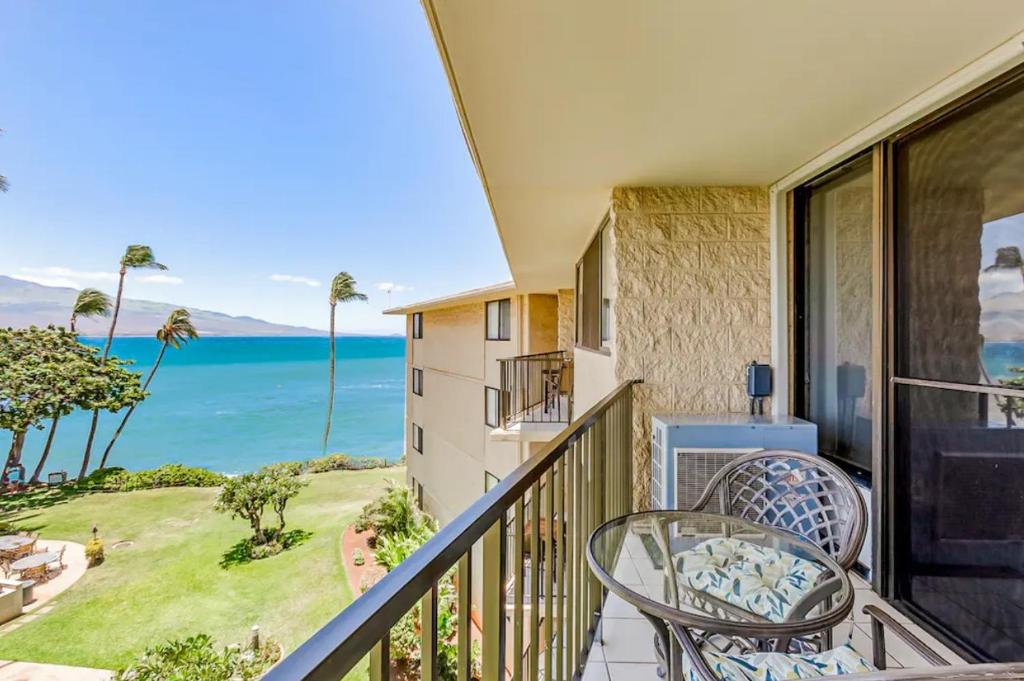 a balcony with a table and chairs and the ocean at Condos in Kana'i A Nalu in Wailuku