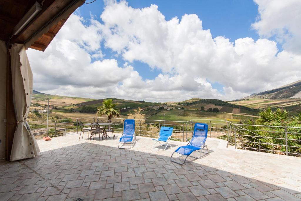 a patio with blue chairs and a table with a view at Case Navarra in Balata di Baida