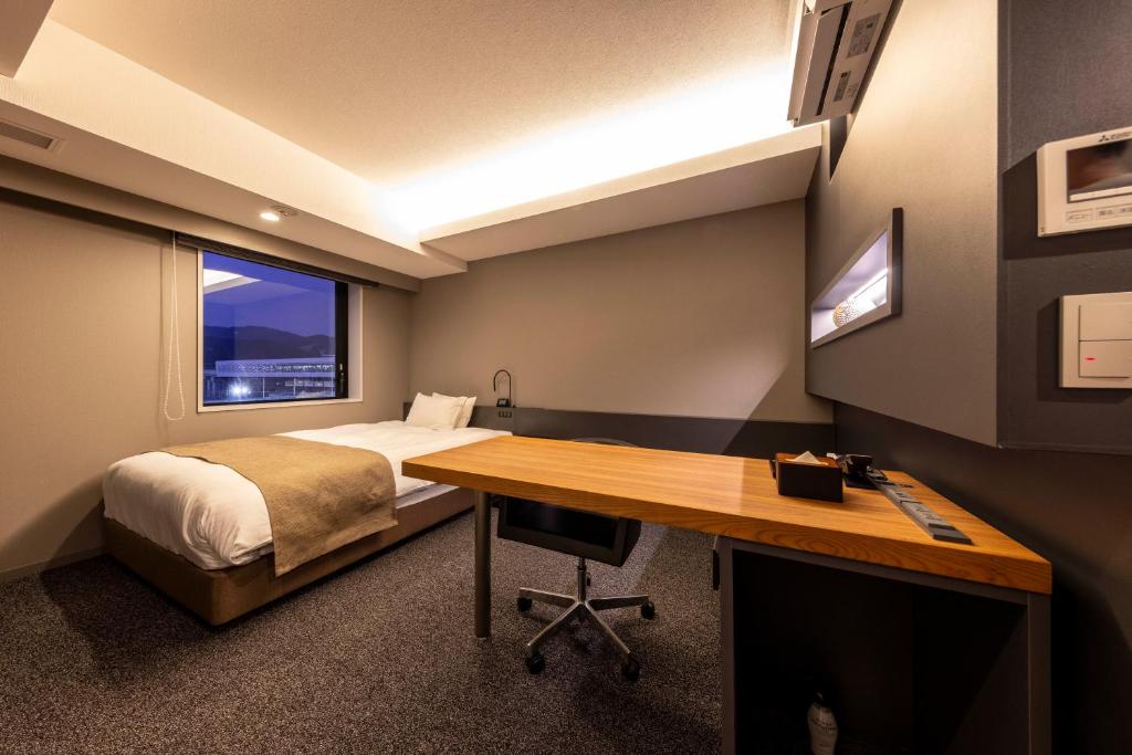 um quarto com uma cama, uma secretária, uma cama e uma janela em Hotel Granbinario Tsuruga em Tsuruga