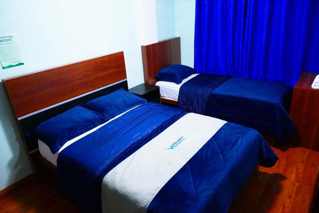 Hostal Valle Andino في El Tambo: سريرين في غرفة نوم مع ملاءات زرقاء وبيضاء