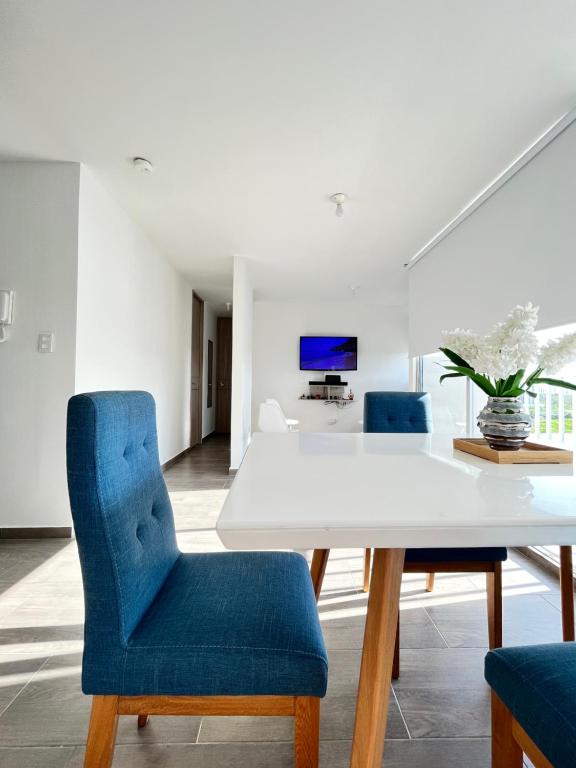 a dining room with a white table and blue chairs at Apartamento 30min del Mar in Cartagena de Indias