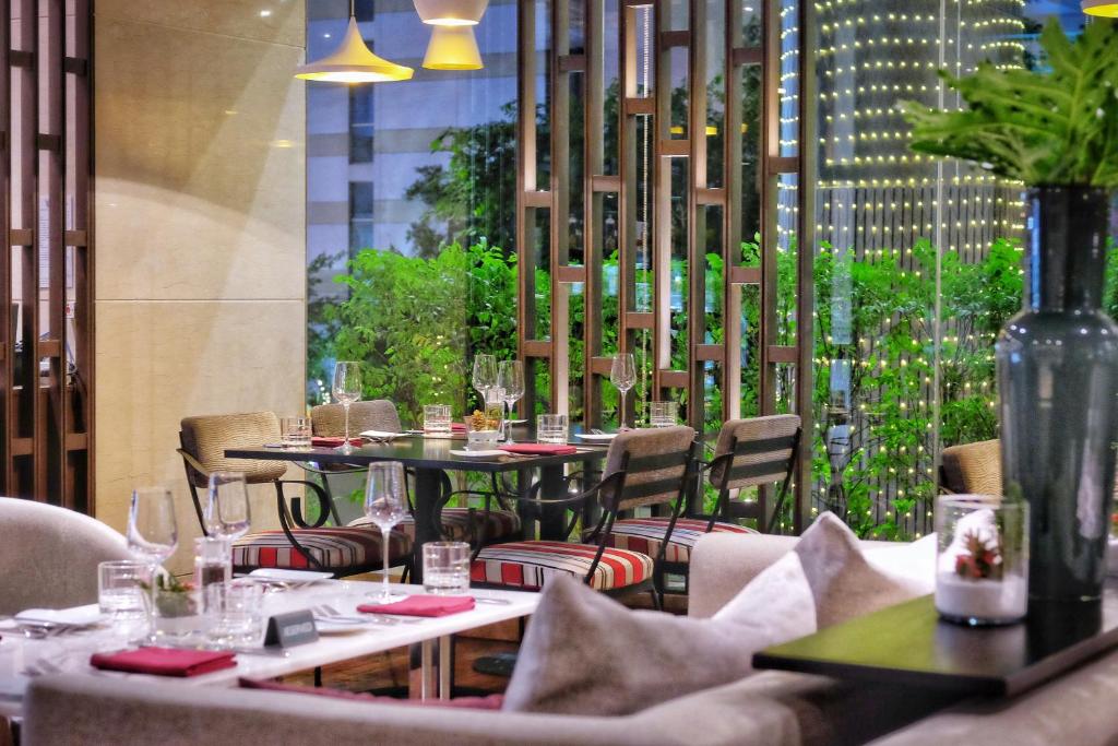 a restaurant with tables and chairs and a large window at Amari Bangkok in Bangkok
