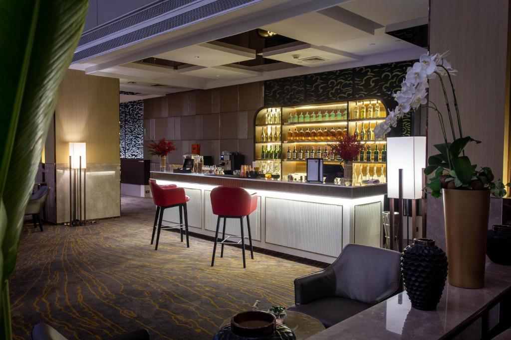 a lobby with a bar with red chairs at Amari Bangkok in Bangkok