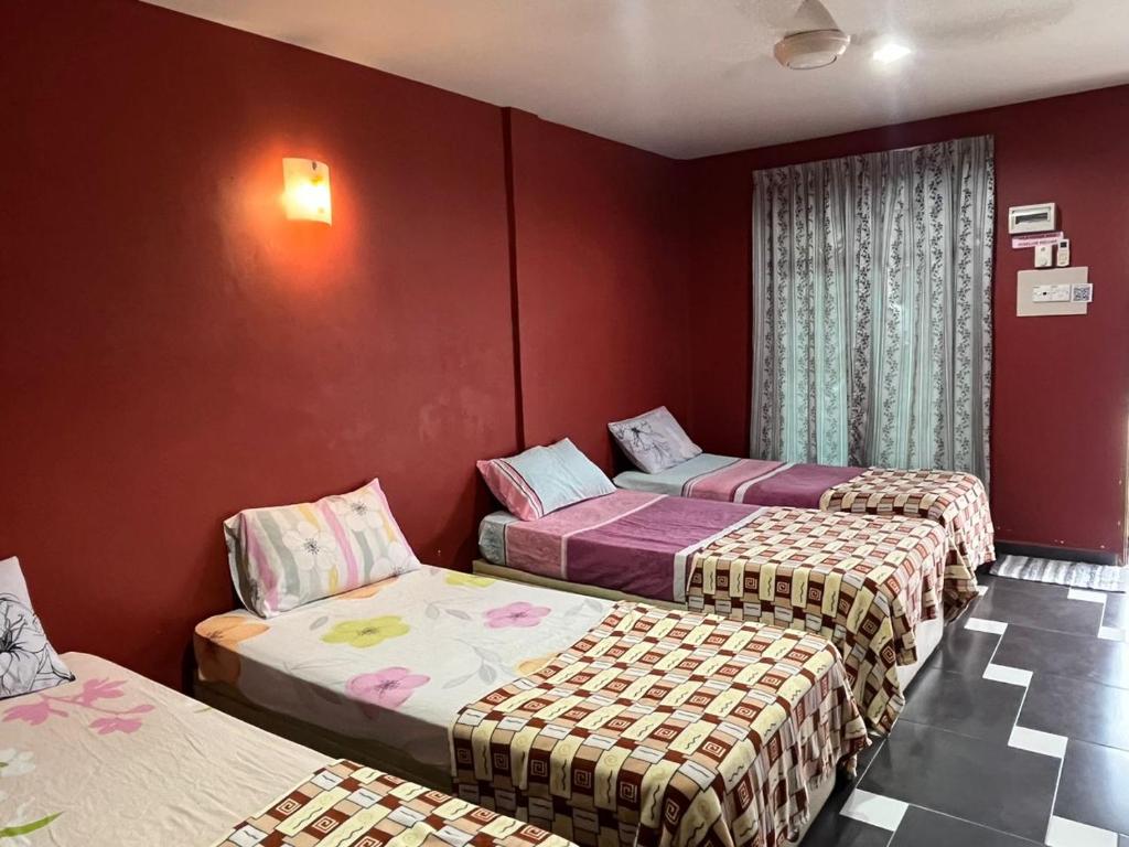três camas num quarto com paredes vermelhas em Ayem Homestay UTHM em Parit Raja