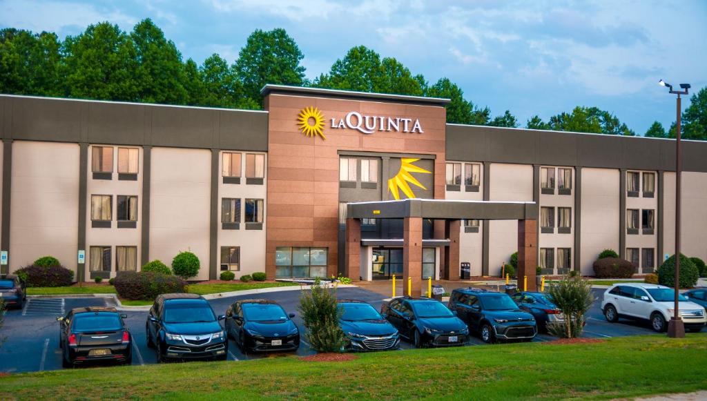 a hotel with cars parked in a parking lot at La Quinta Inn & Suites by Wyndham Fayetteville I-95 in Fayetteville