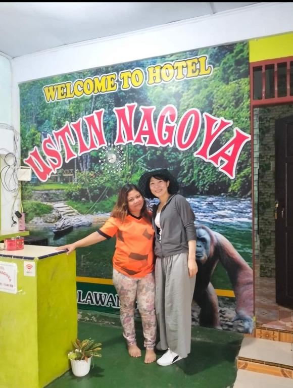 two women standing in front of a welcome to hotel sign at Ustin Nagoya Bukit Lawang Orangutan Trekking & transport You can only stay at the hotel if you book your trekking with us in Bukit Lawang