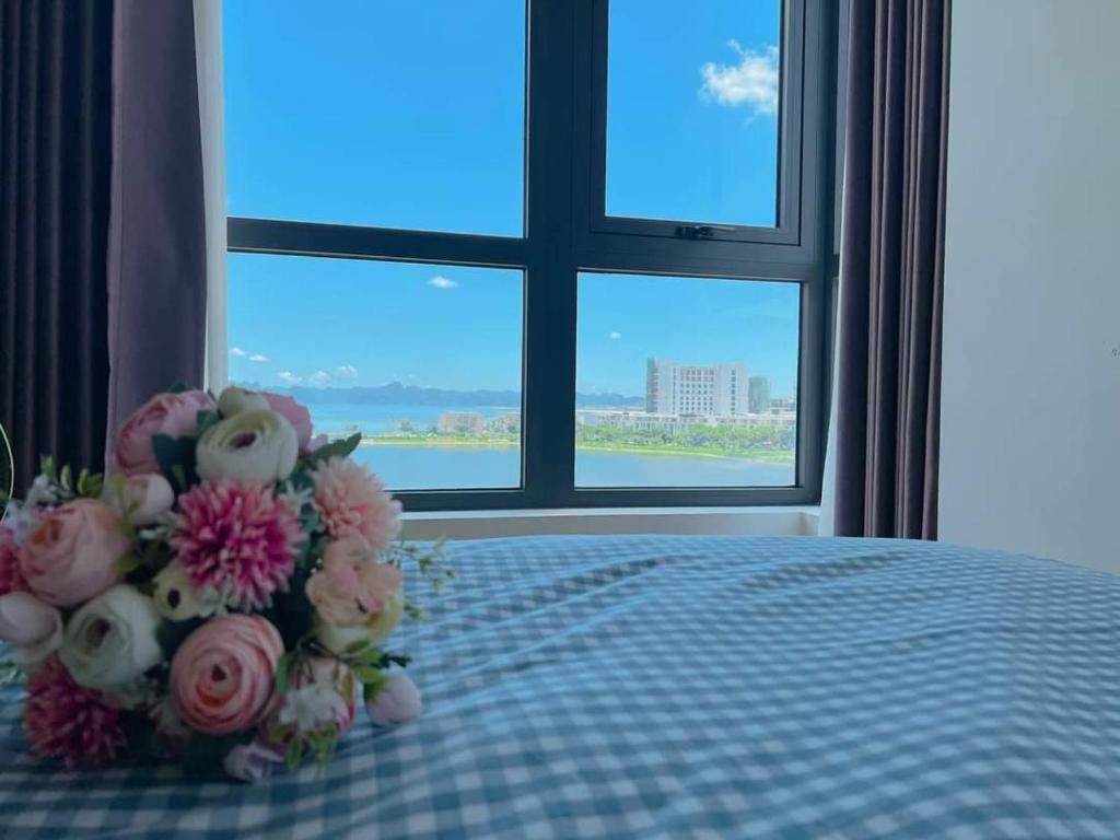 a bouquet of flowers sitting on a bed in front of a window at Annie House Hạ Long Bay in Ha Long