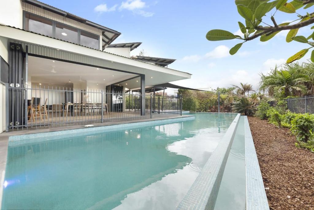 an image of a swimming pool in front of a house at Reef Villa - A Sprawling Waterfront Oasis in Nightcliff