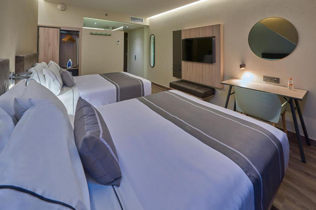Una habitación de hotel con dos camas y un televisor. en City Express Plus by Marriott Mazatlan, en Mazatlán
